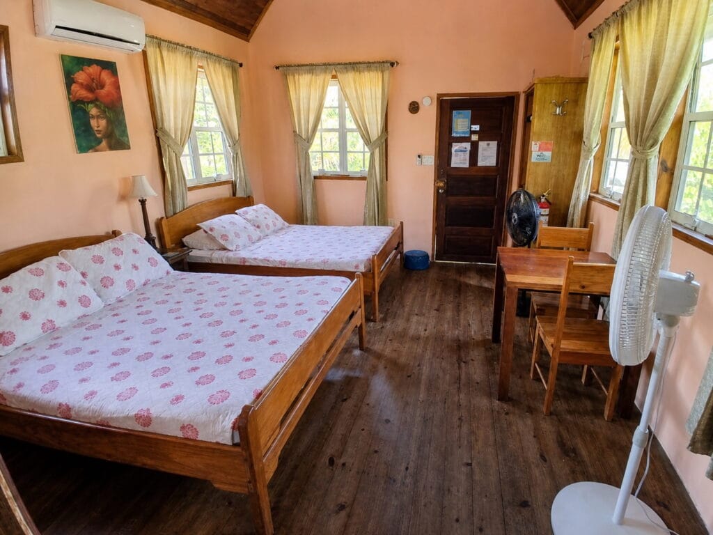 Cabana Menoma interior with two beds, air conditioning and dining area in Placencia, Belize